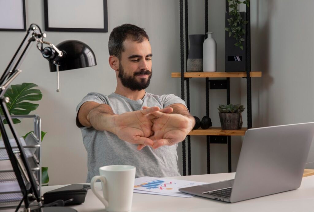 man stretching his arms while working from home Traumatologo Ortopedista en Tijuana https://drcisnerosortopedia.com